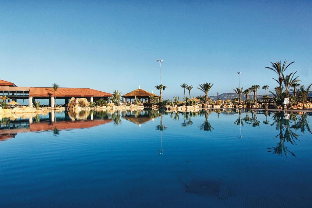 une grande piscine d'eau avec des palmiers et un complexe dans l'établissement Hotel Riu Tikida Dunas - All inclusive, à Agadir