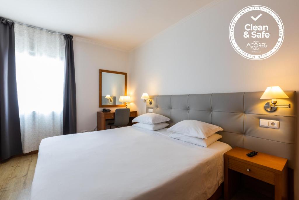 een slaapkamer met een groot wit bed en een raam bij Hotel Arcanjo in Rosário-Lagoa