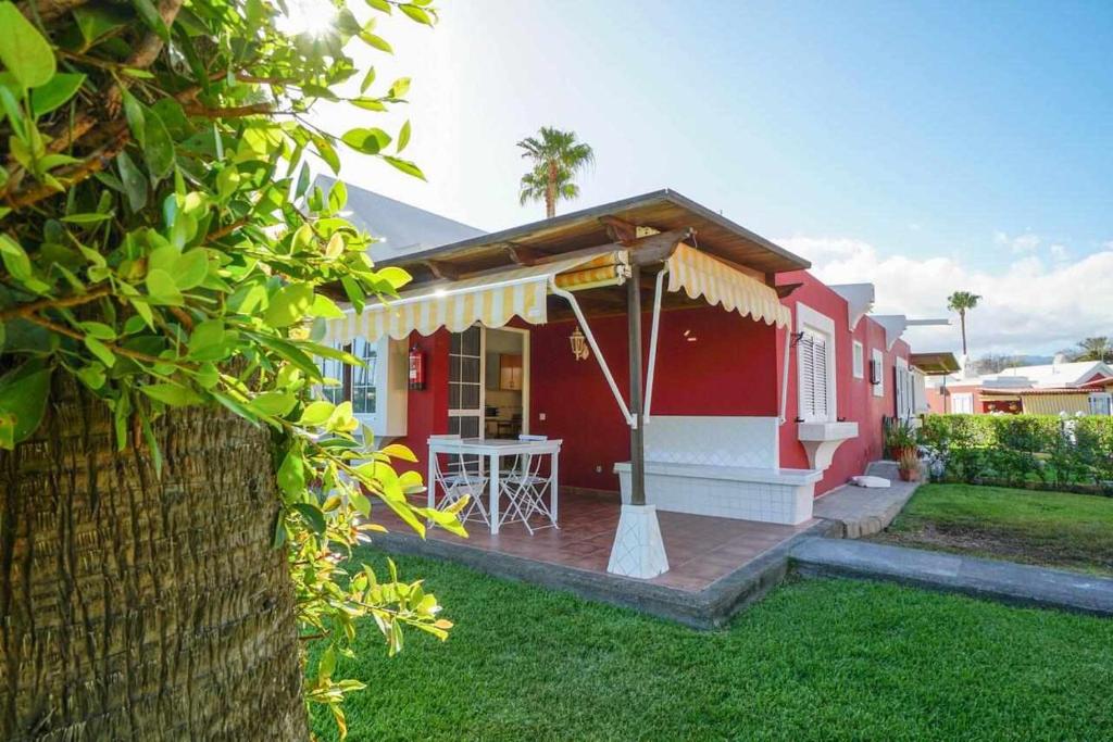 una casa roja y blanca con una mesa en el patio en Los Tunos 81 Air conditioned 1 bedroom, en Maspalomas