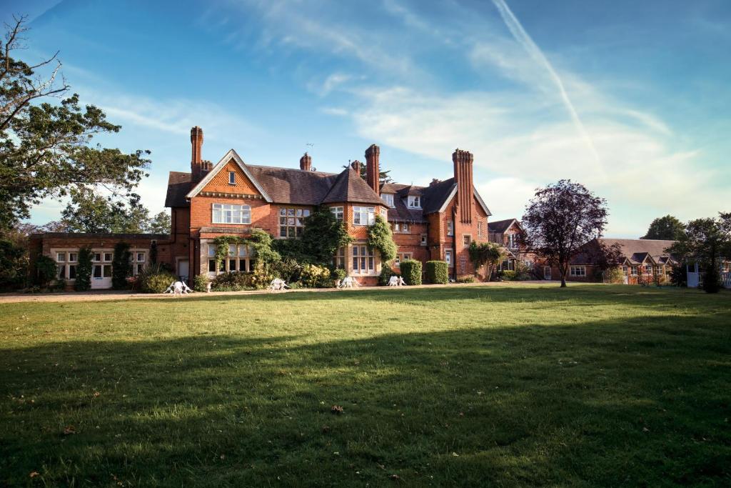 Cantley House Hotel - Wokingham في وكينغهام: منزل من الطوب كبير مع ساحة عشبية كبيرة