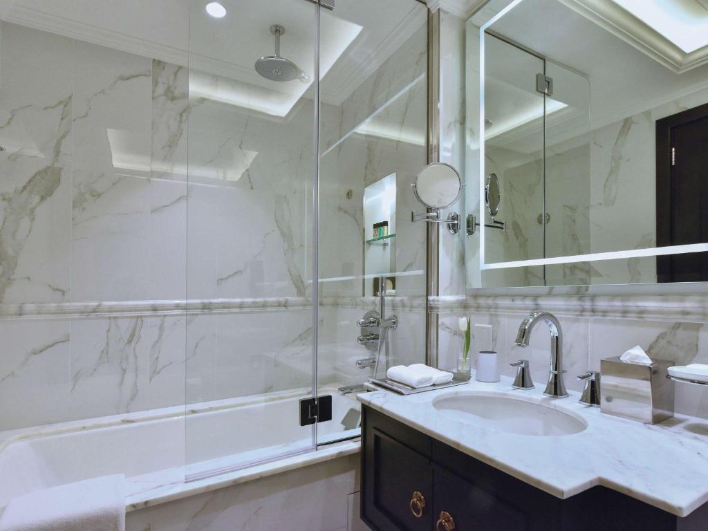 a bathroom with a sink and a large mirror at Mövenpick Hotel Bahrain in Manama