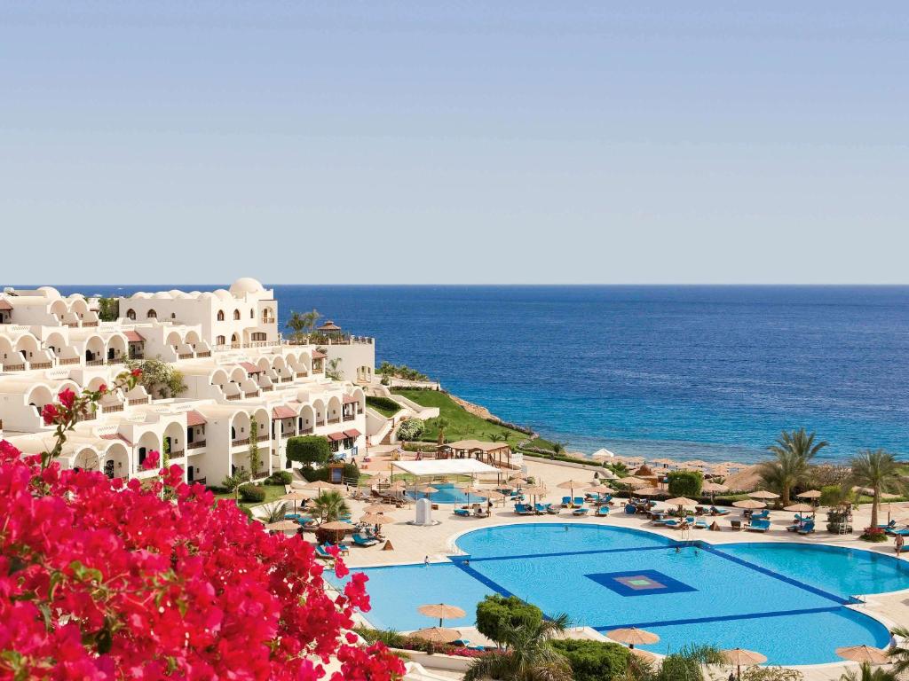 a view of a resort with a swimming pool and the ocean at Movenpick Resort Sharm El Sheikh in Sharm El Sheikh