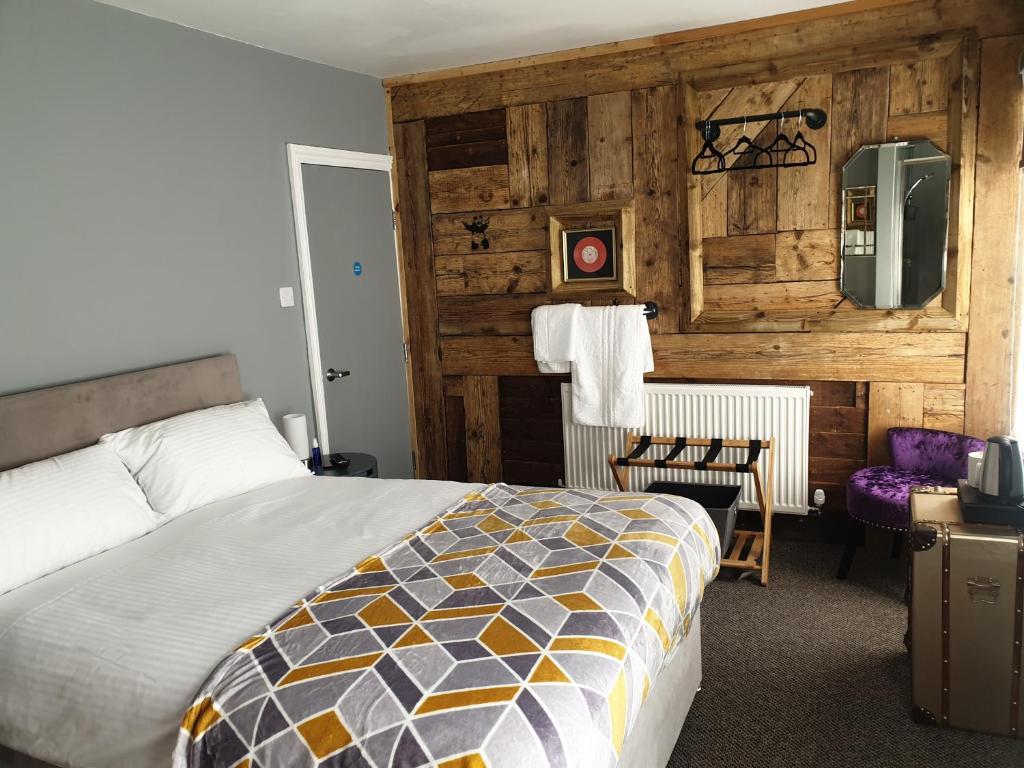 1 dormitorio con 1 cama y pared de madera en Carpenters Arms en Boston