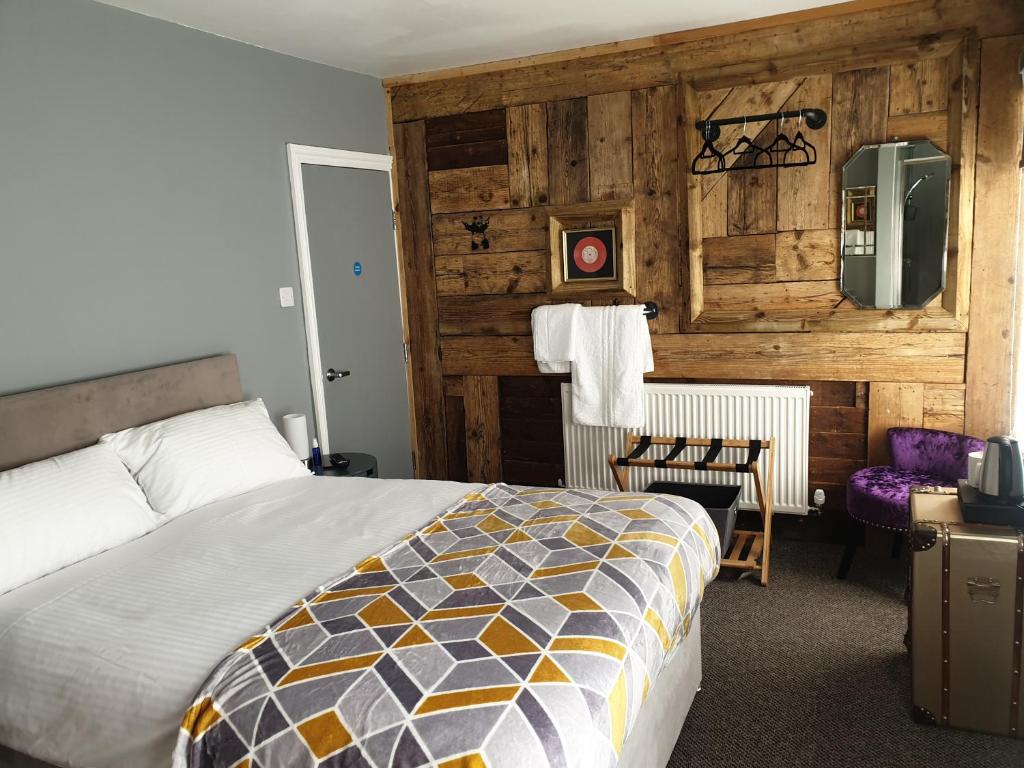 a bedroom with a bed and a wooden wall at Carpenters Arms in Boston