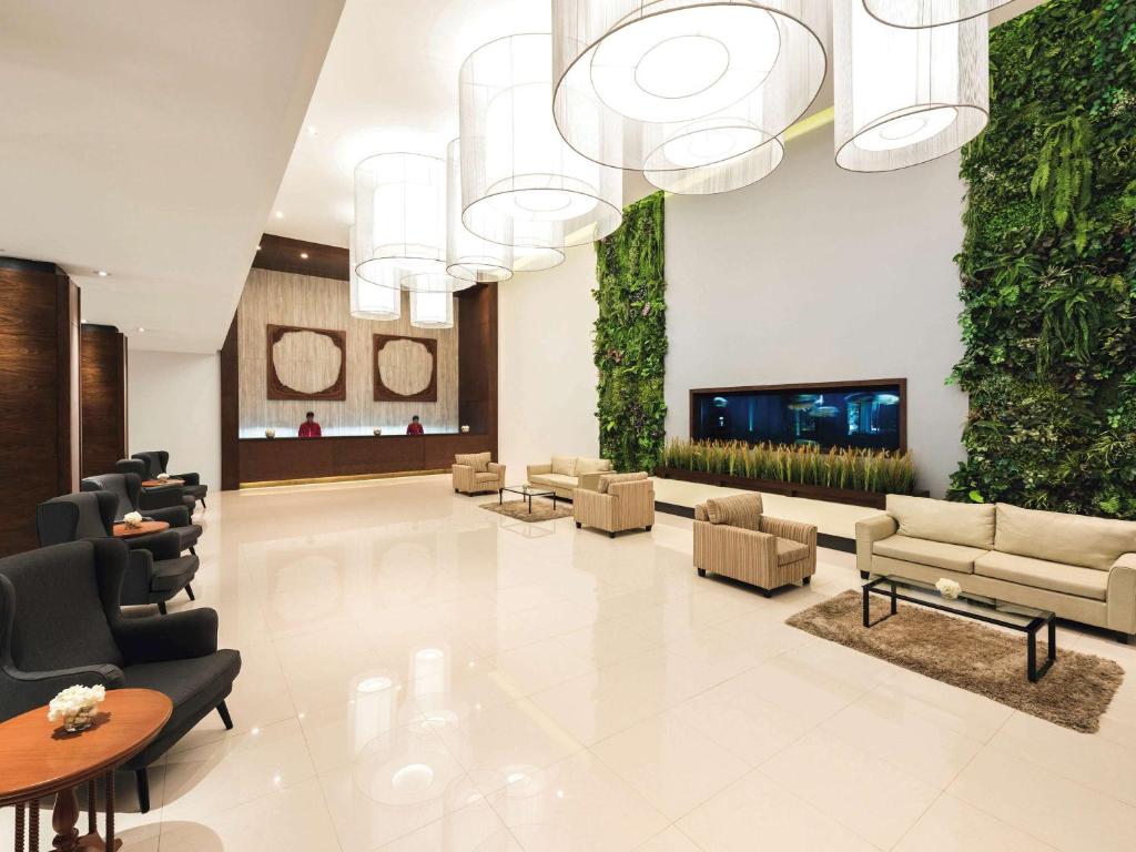 a lobby with couches and a tv in a building at Movenpick Suriwongse Hotel Chiang Mai in Chiang Mai