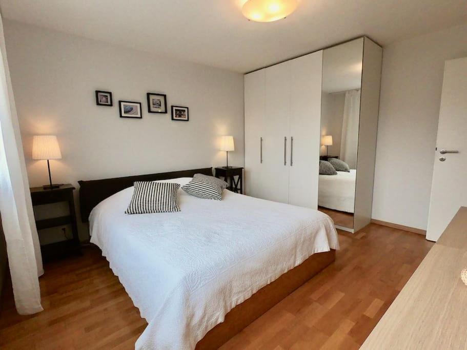 ein Schlafzimmer mit einem großen weißen Bett und einem Spiegel in der Unterkunft Comfortable, sunny, quiet, good location! in Lausanne