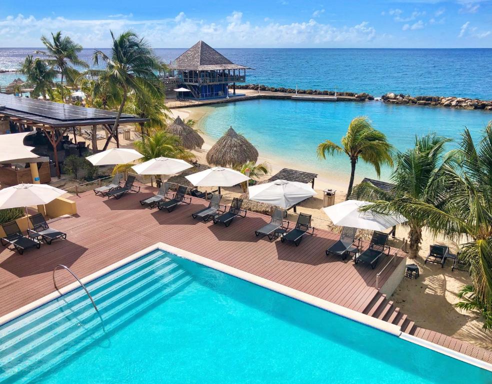 
a beach area with chairs, tables and umbrellas at Curacao Avila Beach Hotel in Willemstad
