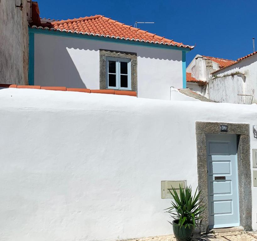 a white wall with a door and a house at Casa Pescador Peniche in Peniche