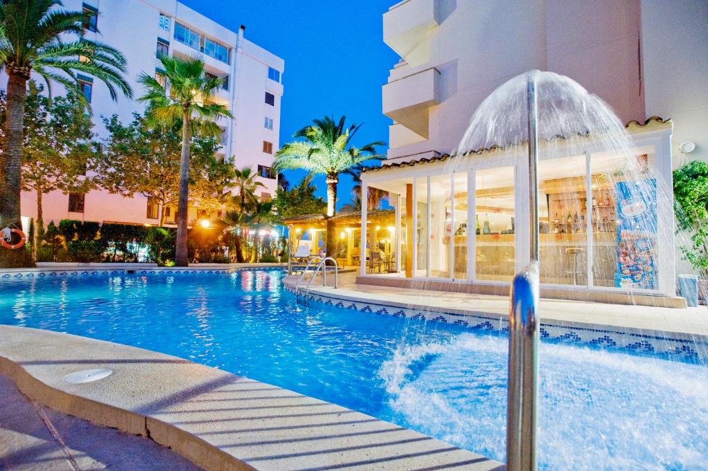 a swimming pool with a fountain in front of a building at Aparthotel Cap De Mar in Cala Bona