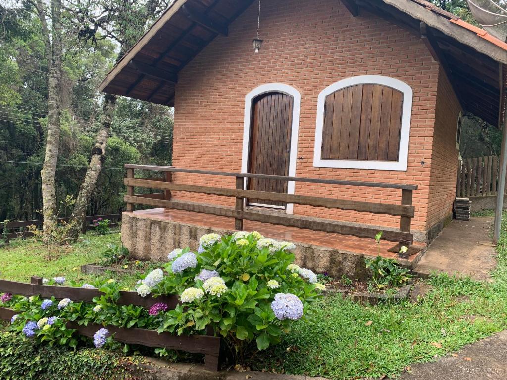 a small brick house with a bench and flowers at Chalés Lua de Mel in Monte Verde