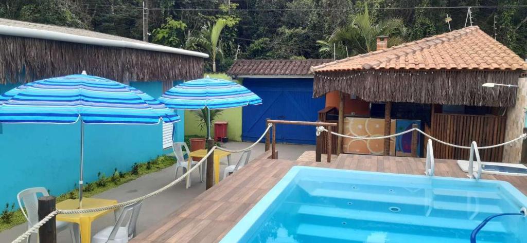 een zwembad met twee parasols en een huis bij Chales Bora Bora - Boraceia in Boracéia