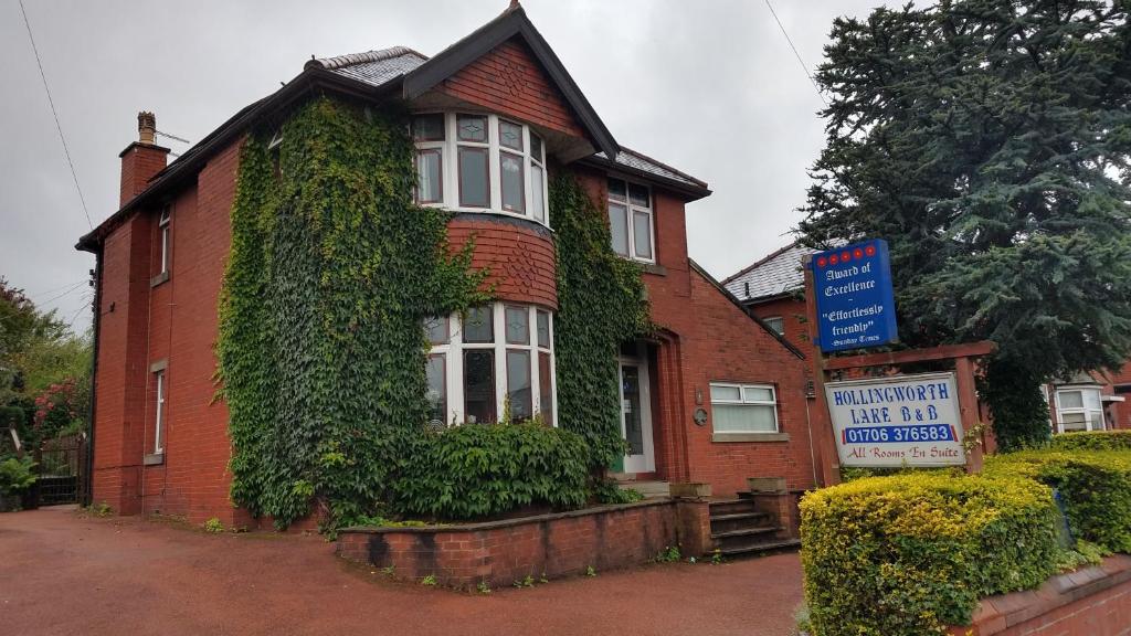 a red brick house with a sign in front of it at Hollingworth Lake Guest House Room Only Accommodation in Littleborough