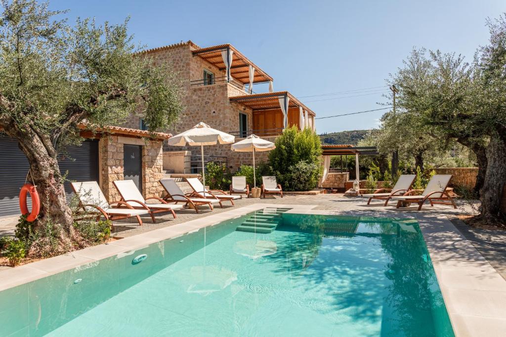 uma piscina com cadeiras e guarda-sóis ao lado de uma casa em Lithos Guesthouse Kardamili em Kardamili