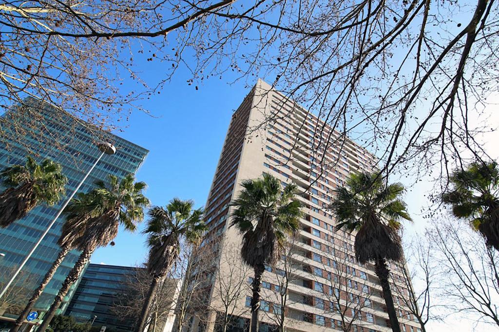 Un edificio alto con palmeras delante. en Panoramic in Travel, Parque das Nações, en Lisboa