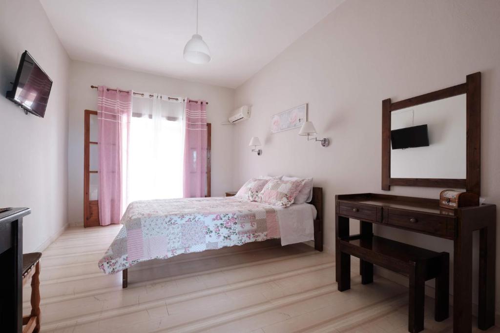 a bedroom with a bed and a mirror and a table at Olive Garden Studios & Apartments in Acharavi