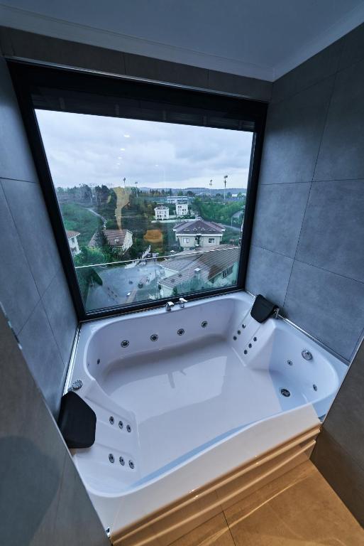 a bath tub in a room with a large window at Selini Hotel İstanbul Airport in Istanbul