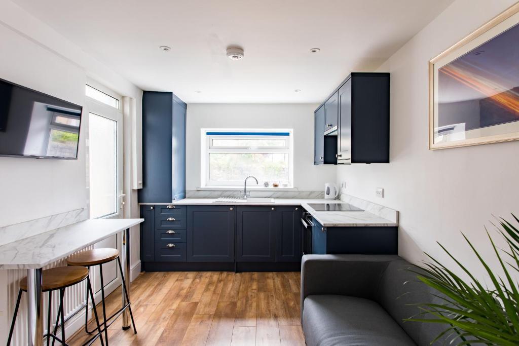 een keuken met blauwe kasten, een wastafel en een bank bij FREE PARKING -2 Bed Apartment, 7mins to City Centre - by StirkMartin in Cardiff