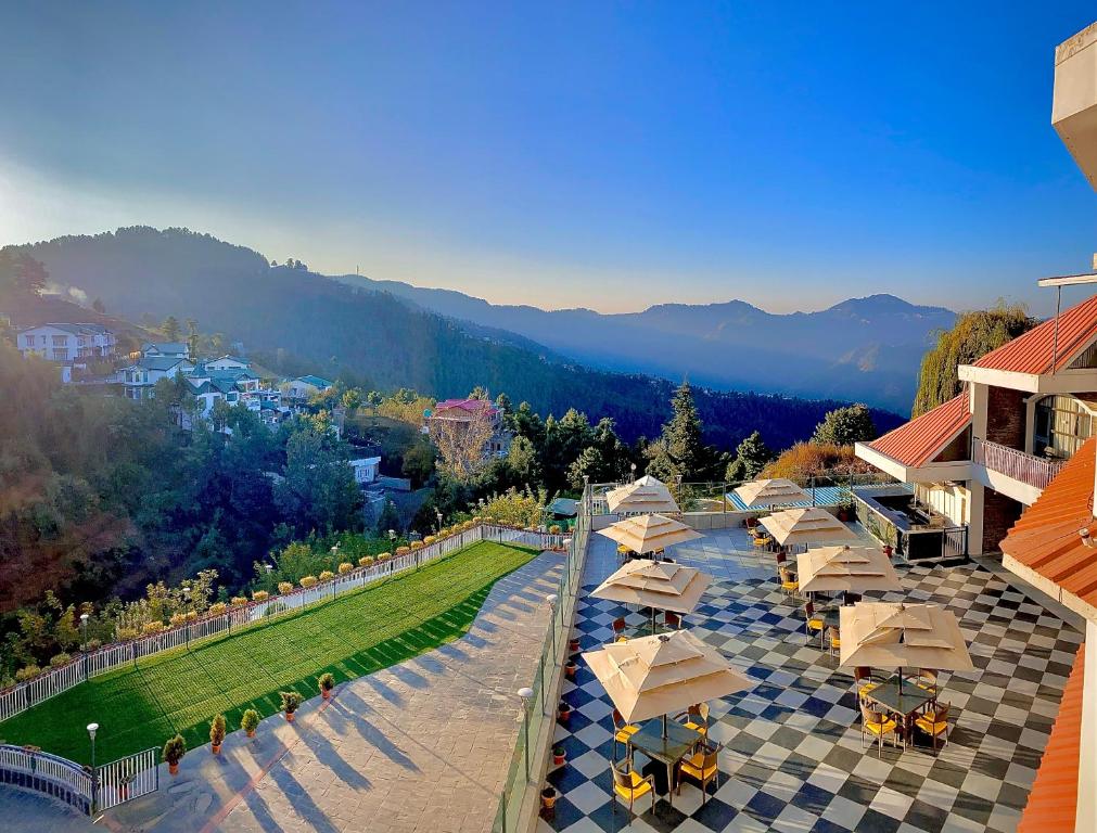an aerial view of a resort with tables and umbrellas at Marigold Sarovar Portico Shimla with Heated pool and AC Rooms-A Resort cottage and SPA in Shimla