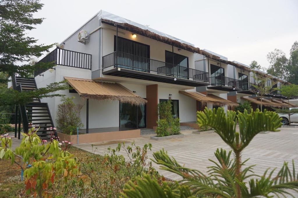 un gran edificio blanco con balcones y aparcamiento en Suwi Coco Ville Resort, en Ubon Ratchathani