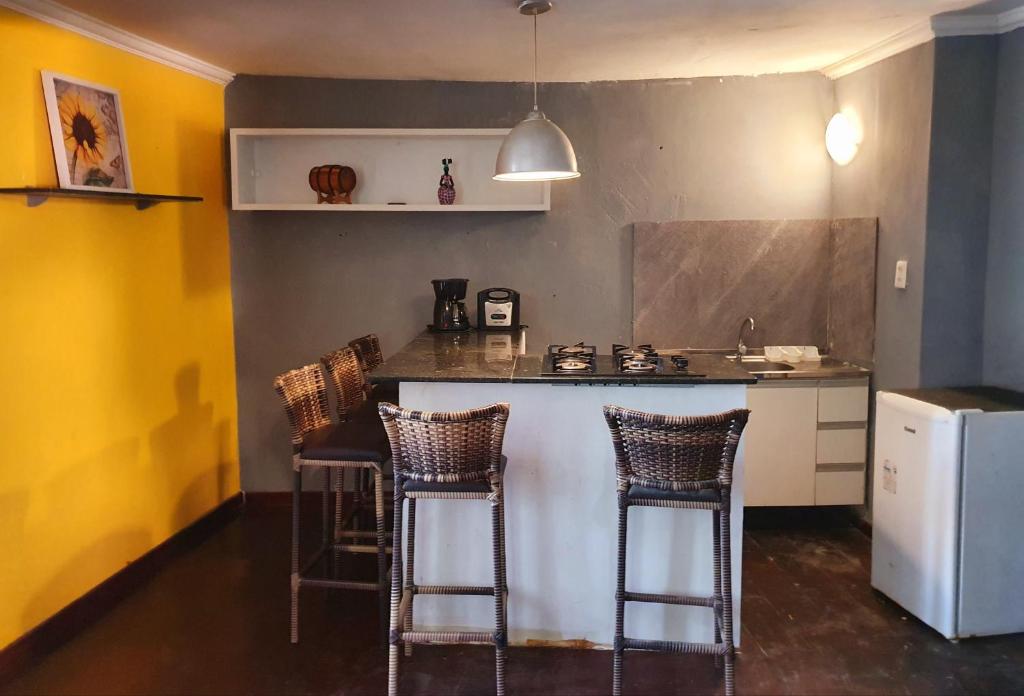 une cuisine avec trois tabourets de bar et un comptoir dans l'établissement Flat dos Ventos, à Morro de São Paulo