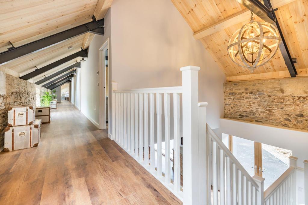 a hallway with wooden ceilings and a staircase with a chandelier at Kingston Estate in Staverton