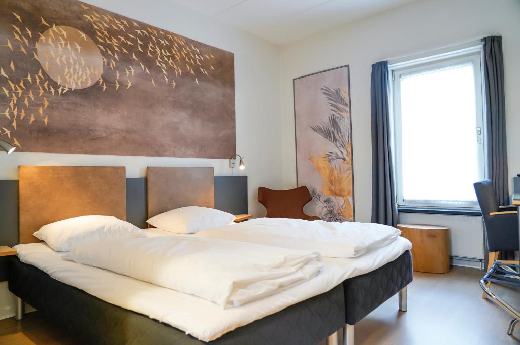 a bedroom with a large bed with a large painting on the wall at City Hotel Nattergalen in Odense