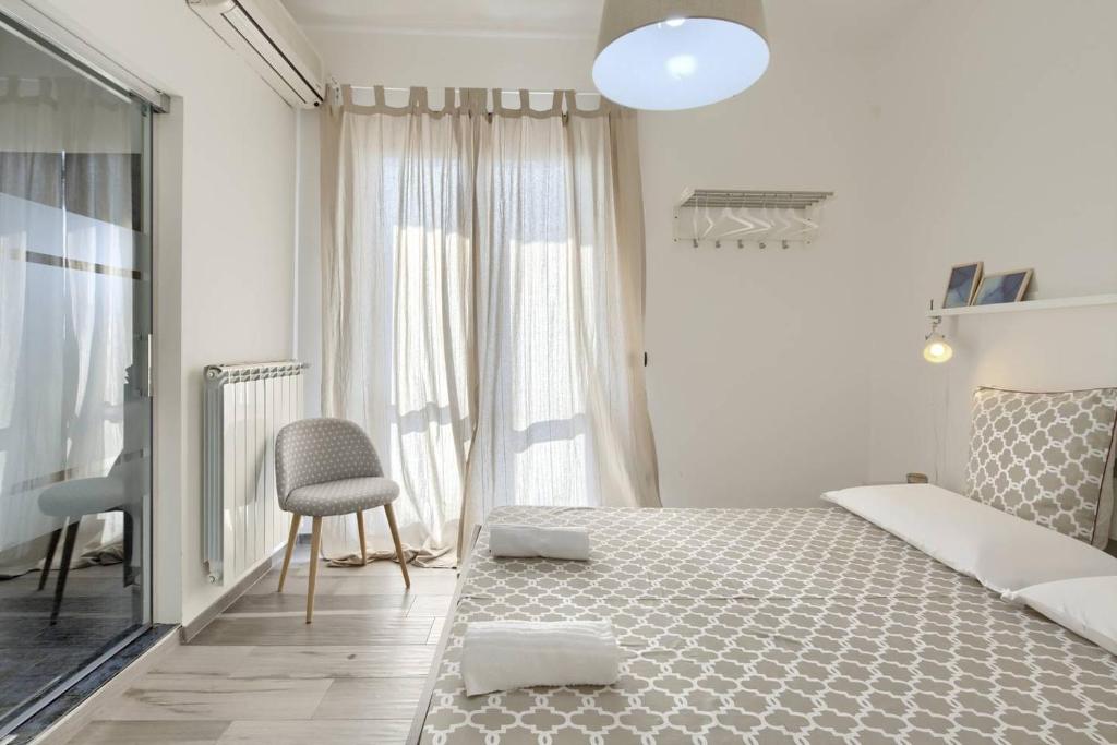 - une chambre blanche avec un grand lit et une chaise dans l'établissement Emozioni D'artista, à Salerne