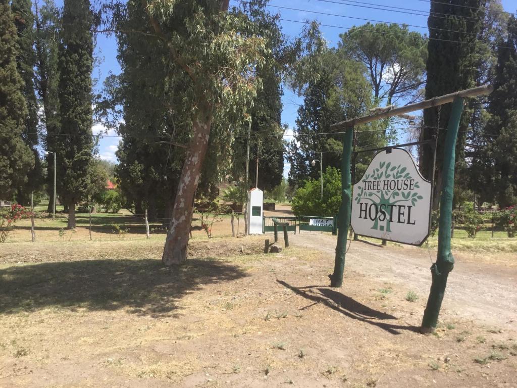 un cartel en un parque junto a un árbol en Tree House Hostel en Salto de las Rosas