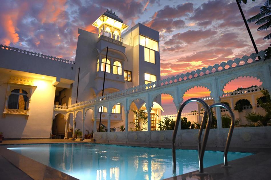 a large building with a swimming pool in front of it at Royal Heritage Haveli Udaipur in Udaipur