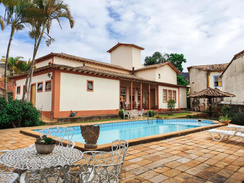 a villa with a swimming pool and a house at Pousada Quinta Do Conde in Tiradentes