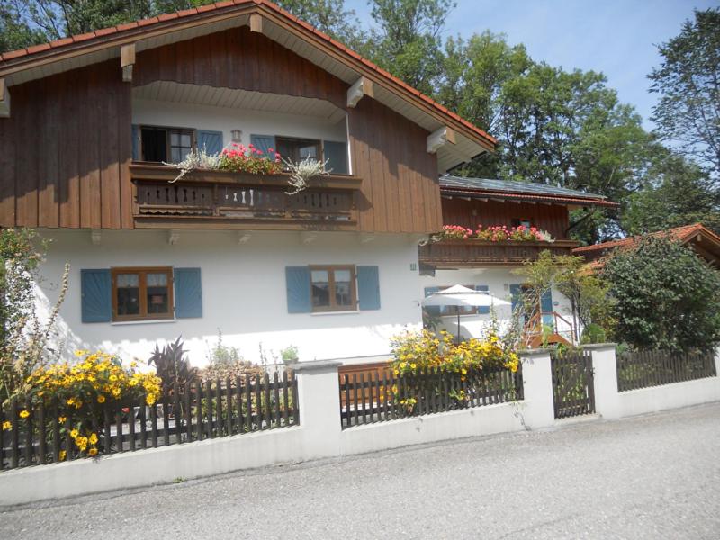 una casa con una valla y flores delante de ella en Ferienwohnung Riepertinger, en Bad Feilnbach