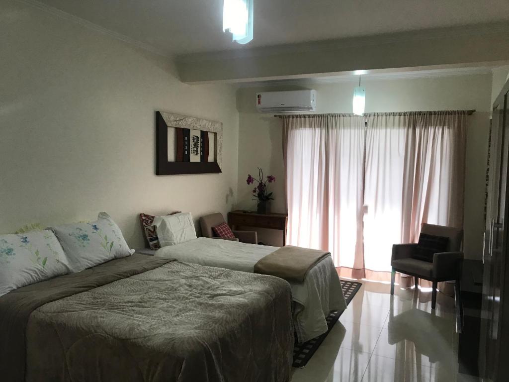 ein Schlafzimmer mit einem Bett, einem Sofa und einem Fenster in der Unterkunft Aconchego próximo à Cascanéia e Blumenau in Gaspar