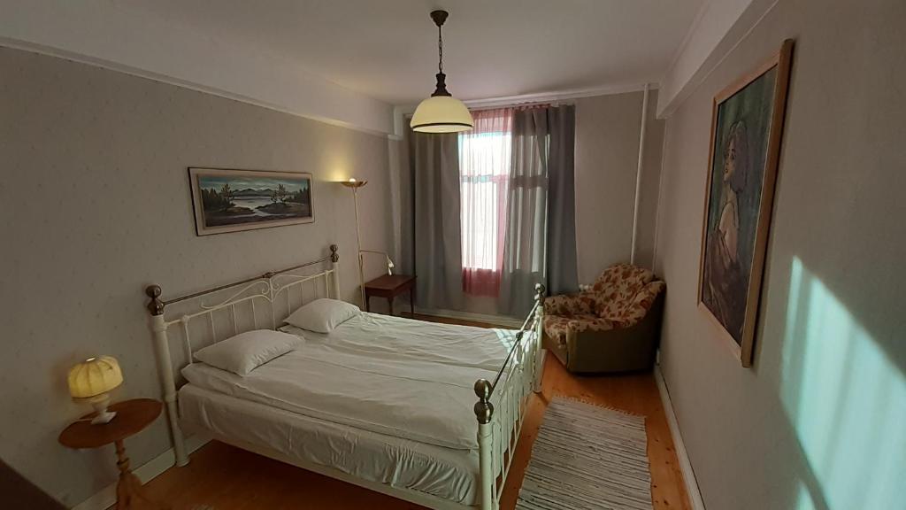 um quarto com uma cama, uma cadeira e uma janela em Majakovski Family Suite em Sillamäe