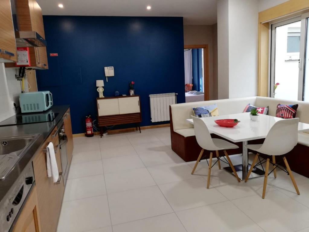 cocina con mesa, sillas y pared azul en Lovely Apartment @ Aveiro's Downtown, en Aveiro
