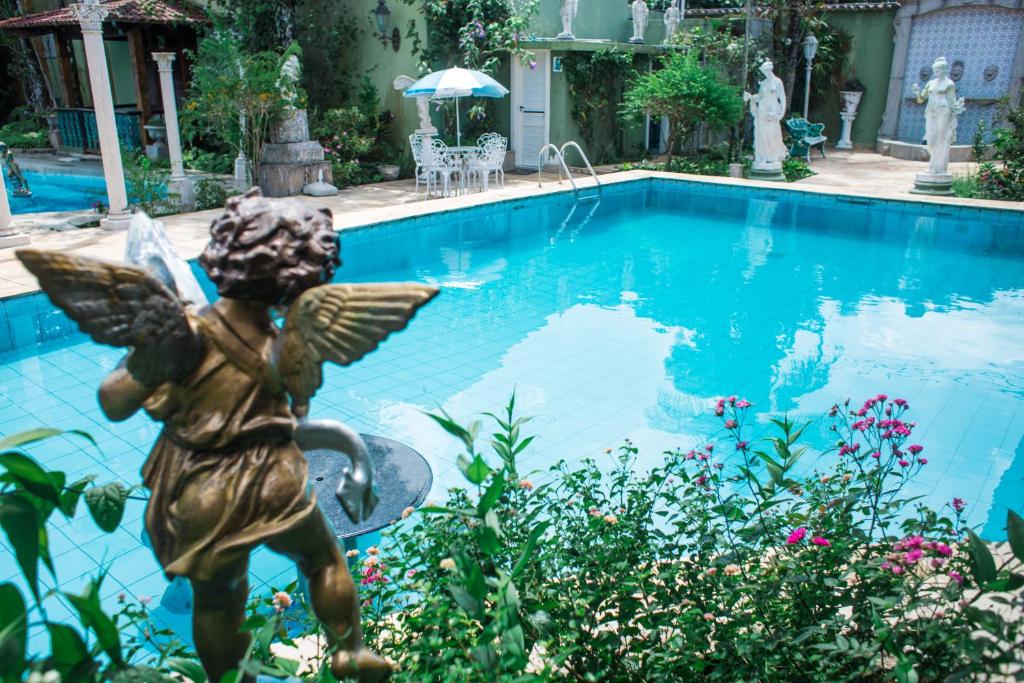 une statue d'un ange à côté d'une piscine dans l'établissement Pernambuco Club House, à Guarujá