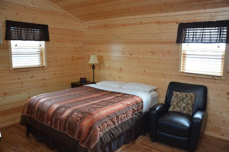 a bedroom with a bed and a chair and two windows at Roosevelt Inn & Suites in Watford City