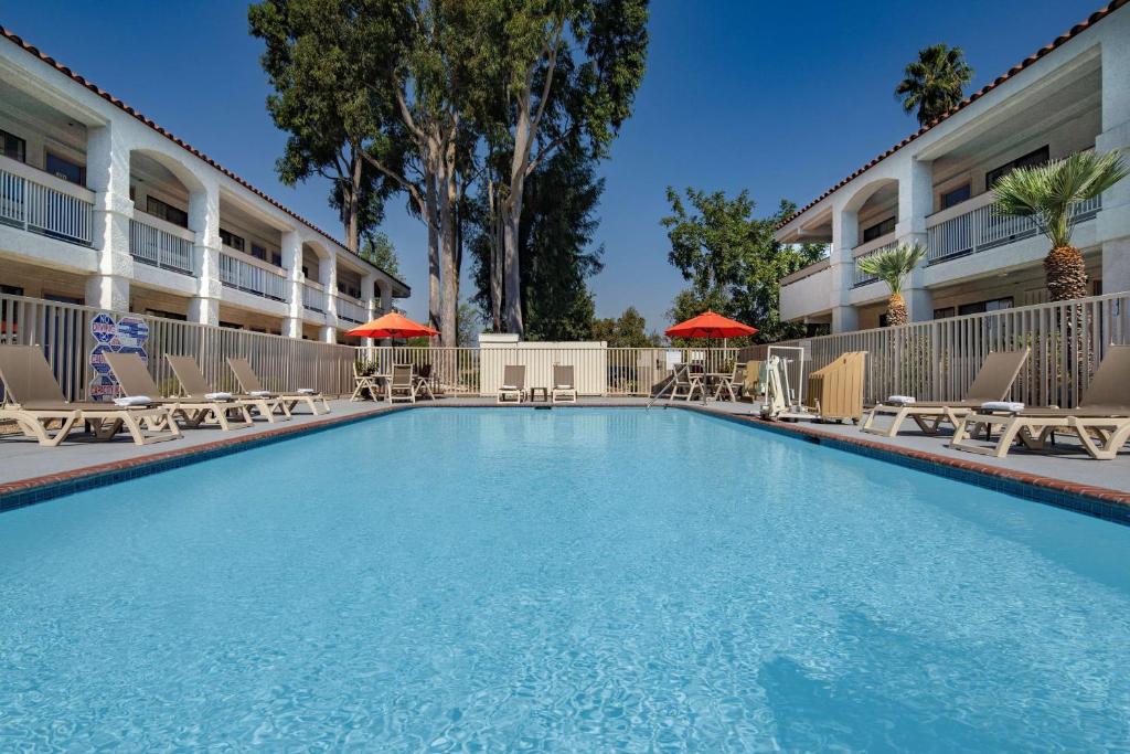 a large swimming pool in a hotel with chairs and umbrellas at Motel 6-Thousand Oaks, CA in Thousand Oaks
