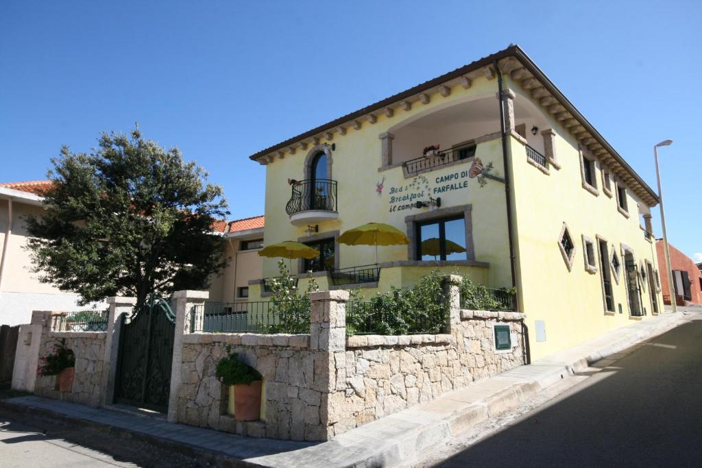 un edificio amarillo con una valla de piedra delante de él en B&B Le Farfalle, en Palau