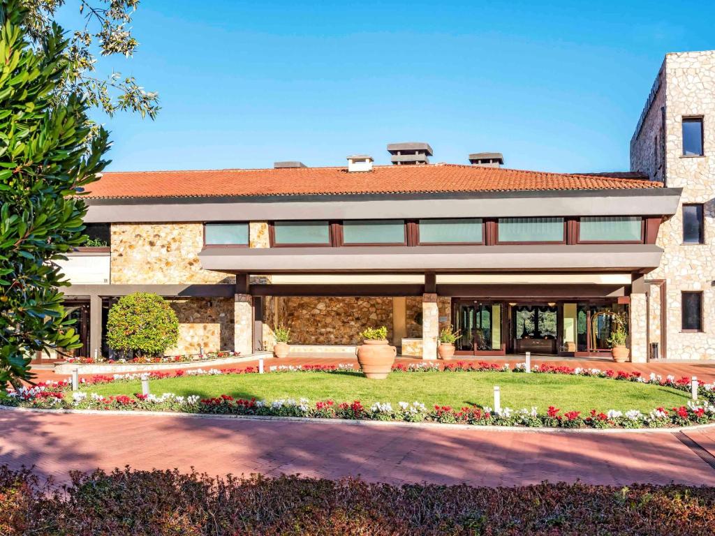 un edificio con giardino di fronte di Mercure Petriolo Siena Terme Spa Hotel a Bagni di Petriolo