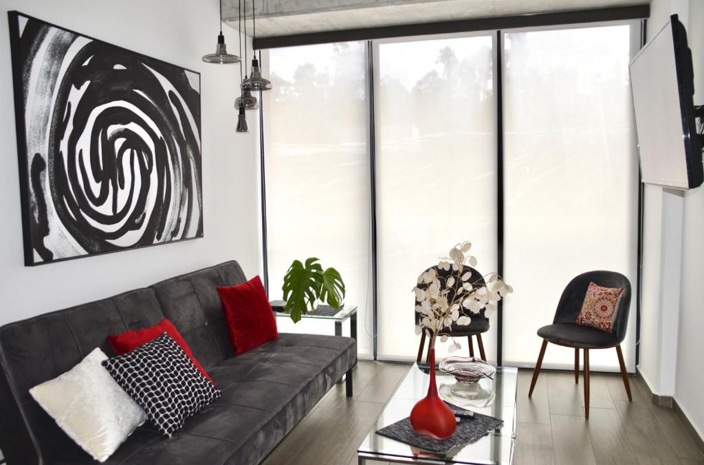 a living room with a black couch and red pillows at Cozy Stays Cayala Apartments 2 in Guatemala