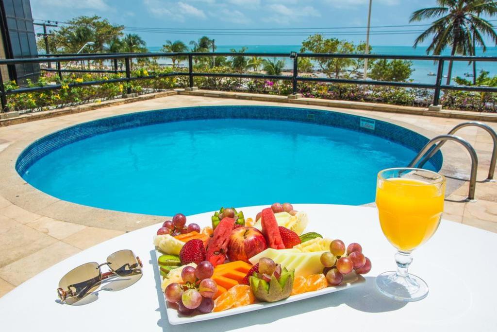 a tray of fruit and juice on a table next to a swimming pool at Flat Golden Fortaleza in Fortaleza