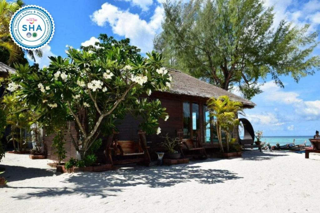 Anda Lipe Resort في كو ليبي: منتجع على الشاطئ به اشجار وورود بيضاء