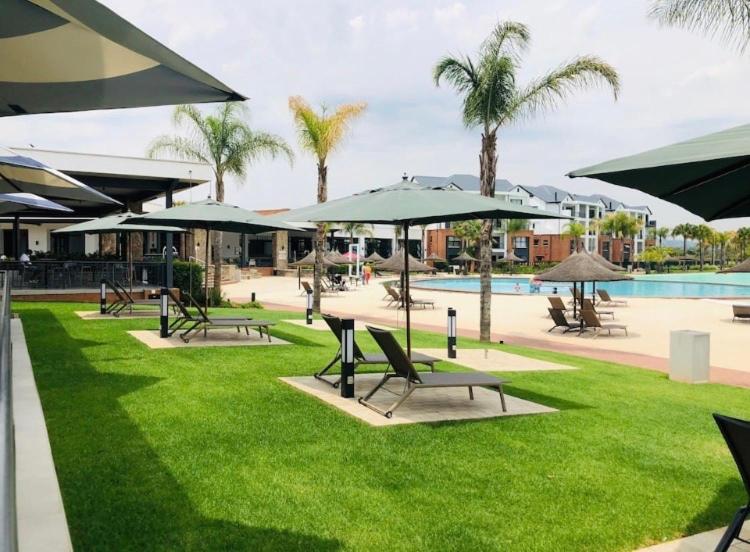 een park met stoelen en parasols en een zwembad bij Serenity in Pretoria