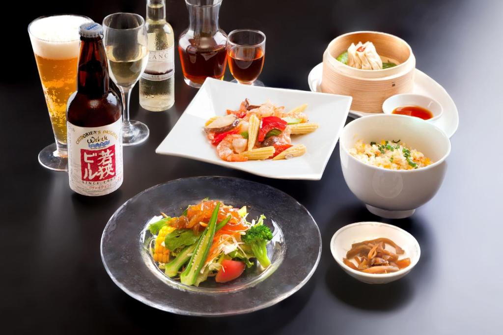 a table with plates of food and a bottle of beer at Hotel Fujita Fukui in Fukui