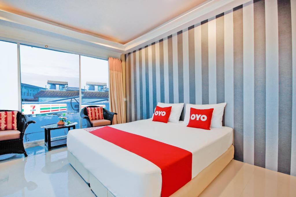a bedroom with a large bed with two red pillows at OYO 1117 Phuket Airport Suites in Nai Yang Beach