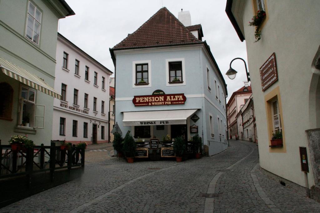 a small white building with a sign on a street at Pension Alfa & Whisky Pub in Tábor