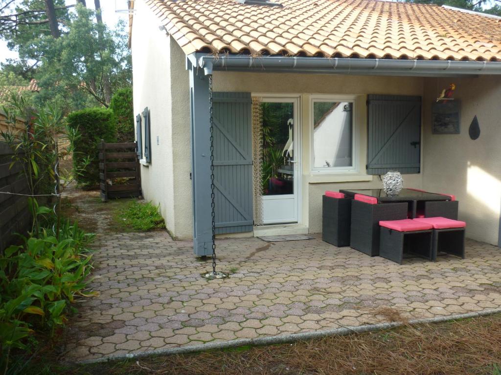 a house with a patio with a table and benches at Tres agreable maison au calme dans la pinede in Lacanau-Océan