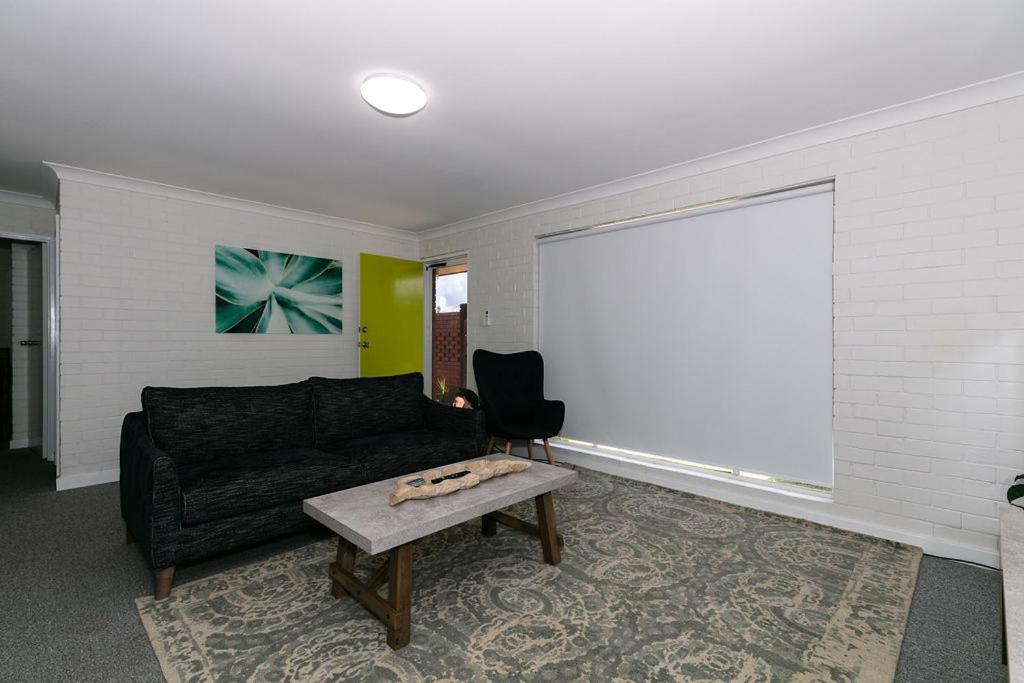 a living room with a black couch and a table at Apparition Apartments in Geraldton