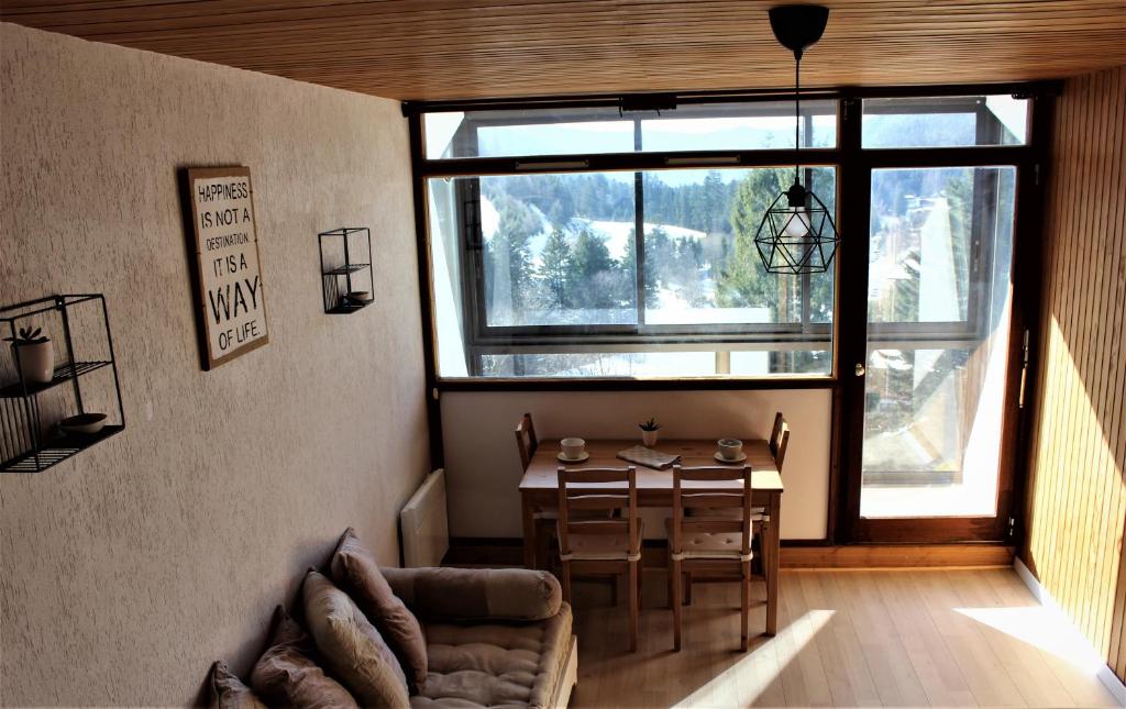 ein Wohnzimmer mit einem Tisch und einem großen Fenster in der Unterkunft Studio sous les pistes avec vue sur la vallée in La Bresse