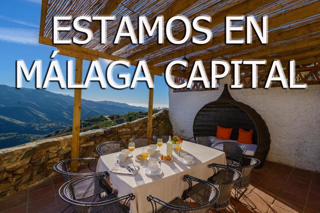 un tavolo e sedie su un balcone con vista sulle montagne di Complejo Rural El Mirador a Málaga